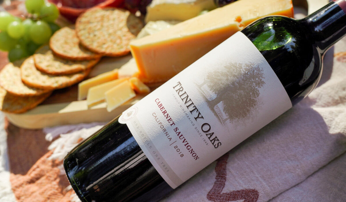 Color image of a bottle Trinity Oaks Cabernet Sauvignon among cheese and crackers.