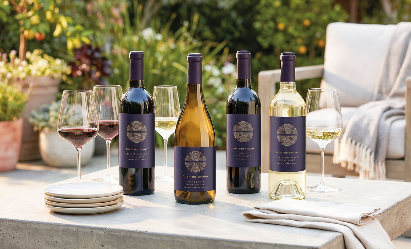Bottles of Quattro Theory Cabernet Sauvignon, Chardonnay, Merlot, and Sauvignon Blanc on an outdoor table setting