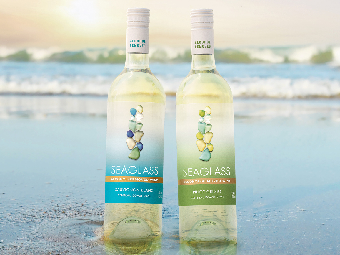 Two wine bottles in the sand. One bottle is SEAGLASS Alcohol-Removed Sauvignon Blanc. The second bottle is SEAGLASS Alcohol-Removed Pinot Grigio.